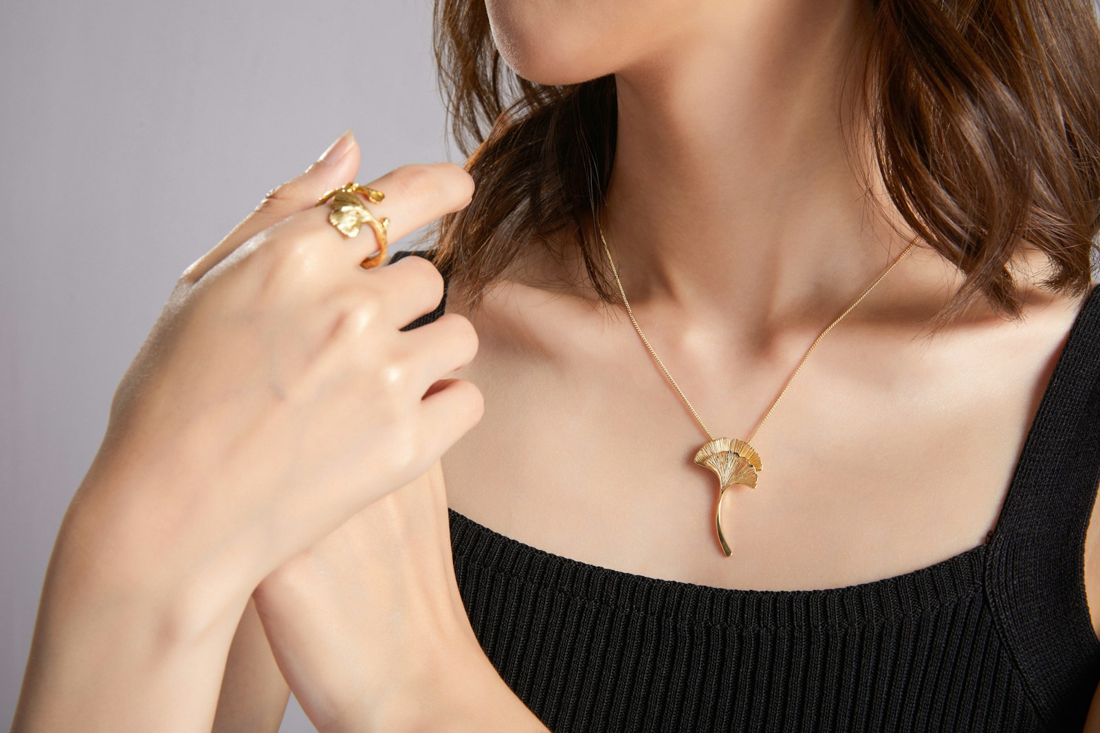 Model wearing a gold pendant necklace and ring